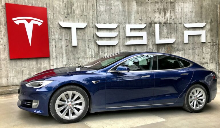 blue coupe parked beside white wall